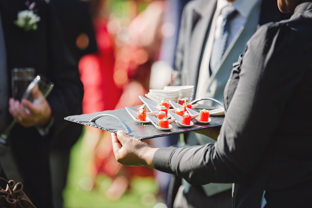 Evento de profesionales en el que esta pasando una bandeja con canapés